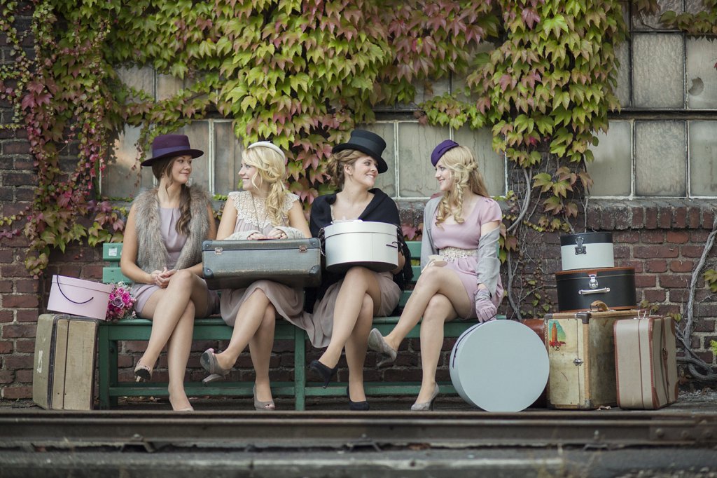 Photo bridesmaids waiting for train with suitcases and hat boxes